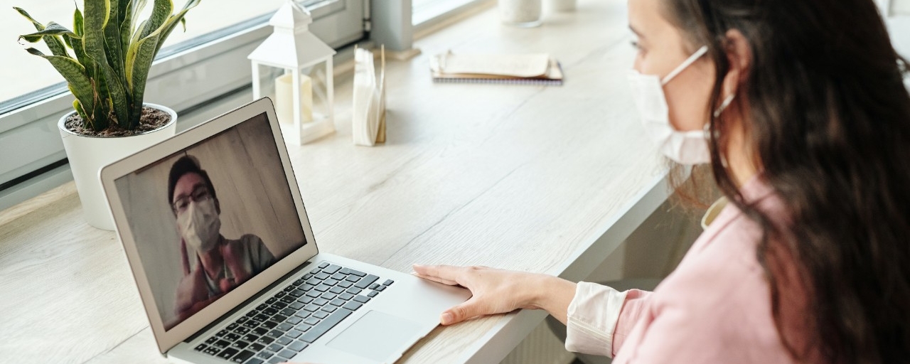 Woman in front of laptop wearing a facemask