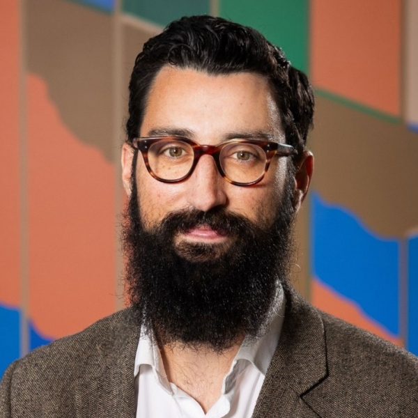 Photo of person wearing glasses, bearded, collared shirt and jacket